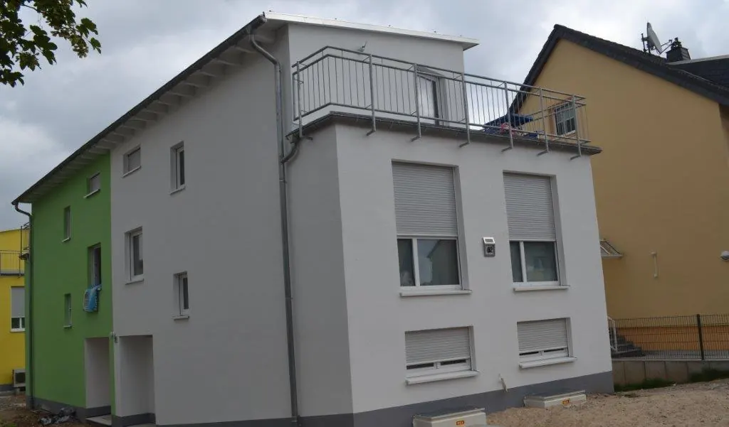 Fertiggestellte Fassade eines Mehrfamilienhauses in Weiß, Grau und Grün